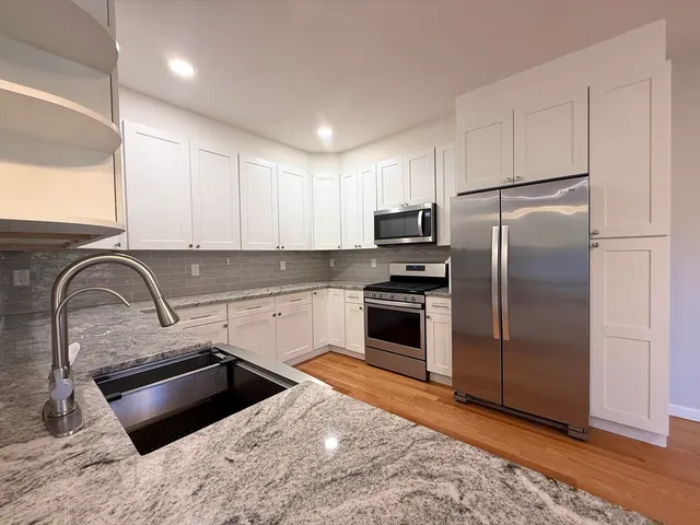 a kitchen with stainless steel appliances granite countertop a refrigerator sink and stove