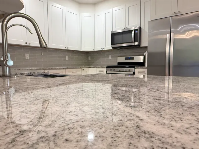 a kitchen with kitchen island a sink stainless steel appliances and a counter top space