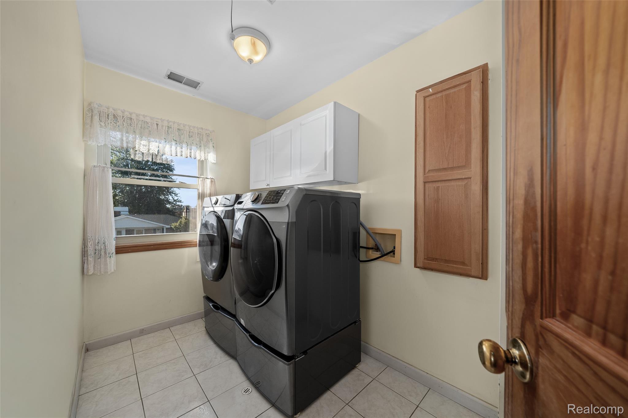 7214 Cardinal Road Algonac, MI 48001 - Photo 11 of 51 Laundry room featuring light tile patterned floors, washing machine and dryer, and cabinet space