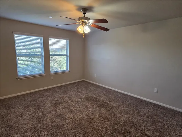 a view of an empty room and chandelier fan