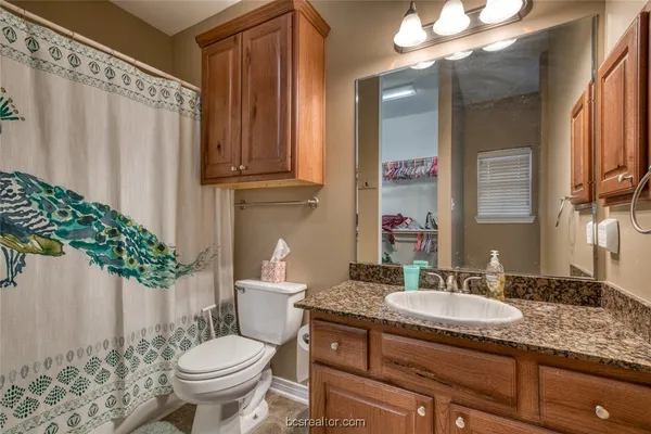 a bathroom with a granite countertop sink toilet and mirror
