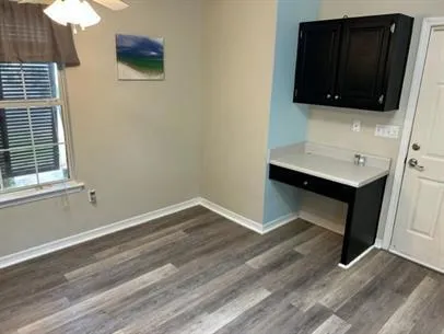 a view of an empty room with wooden floor and a bathroom