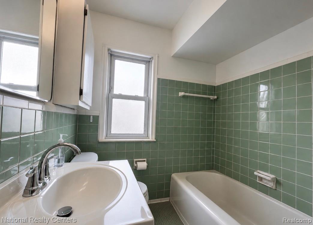 7285 Helen Street Center Line, MI 48015 - Photo 15 of 32 Bathroom featuring green subway tile walls, a white vanity with an integrated sink, and a chrome faucet