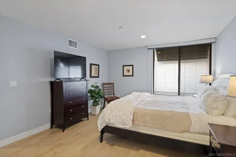 a bedroom with a bed and a flat tv screen on dresser