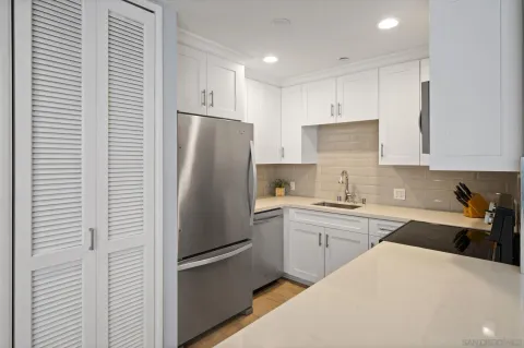 a kitchen with a refrigerator a sink and white cabinets