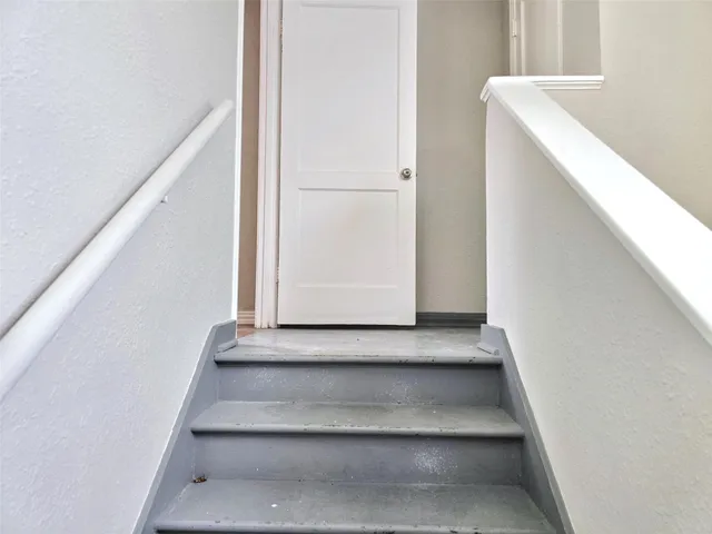 a view of staircase with white walls and white door