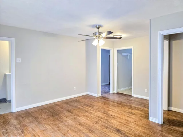 a view of a room with a ceiling fan and hardwood floor