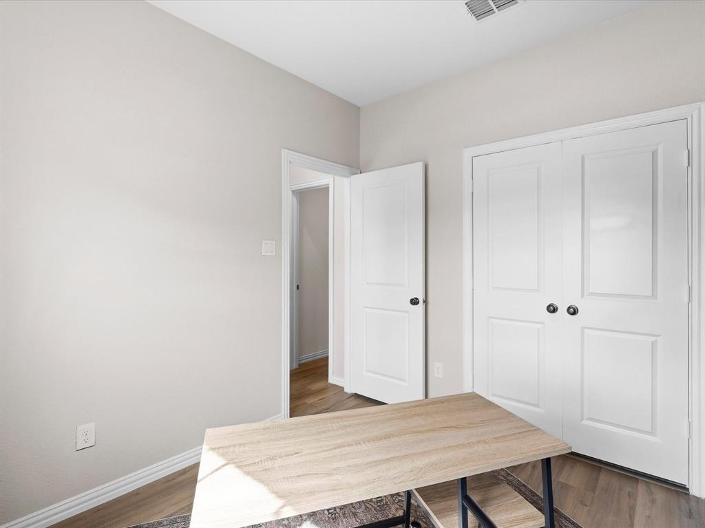 16936 Post Cedar Drive Justin, TX 76247 - Photo 19 of 30 Neutral-toned room with wood-finish flooring, white baseboards, and a white six-panel bifold closet door