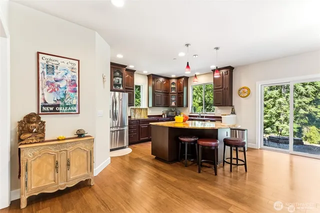 a view of kitchen with stainless steel appliances granite countertop a stove and a dining table with wooden floor