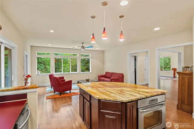 a outdoor kitchen with a stove a sink dishwasher a dining table and chairs with wooden floor