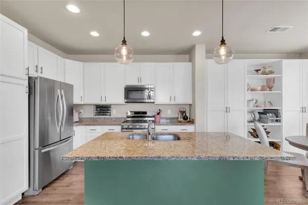 a kitchen with kitchen island granite countertop a refrigerator a stove a sink and a refrigerator