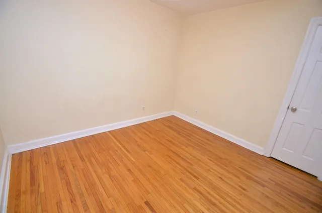 an empty room with wooden floor and a bathroom