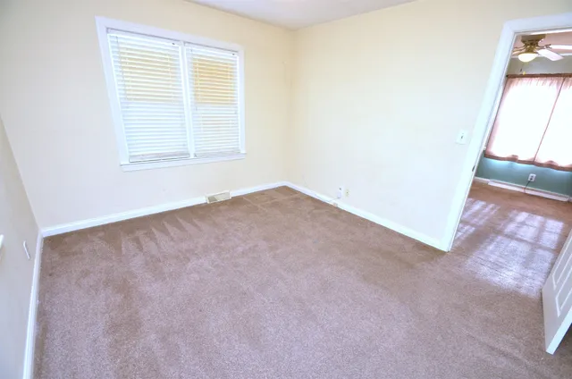 an empty room with kitchen view and wooden floor