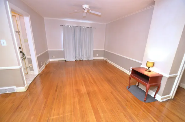 a view of an empty room with wooden floor and a window