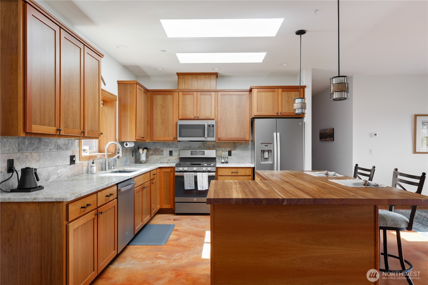 1335 Crestline Terrace Oak Harbor, WA 98277 - Photo 8 of 39 a large kitchen with stainless steel appliances granite countertop a refrigerator a sink dishwasher a stove with wooden cabinets and floor