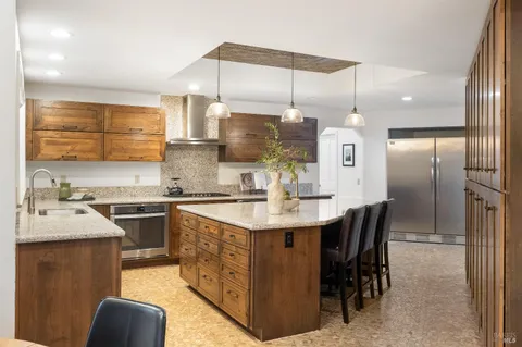 a kitchen with kitchen island granite countertop a sink a counter top space appliances and cabinets