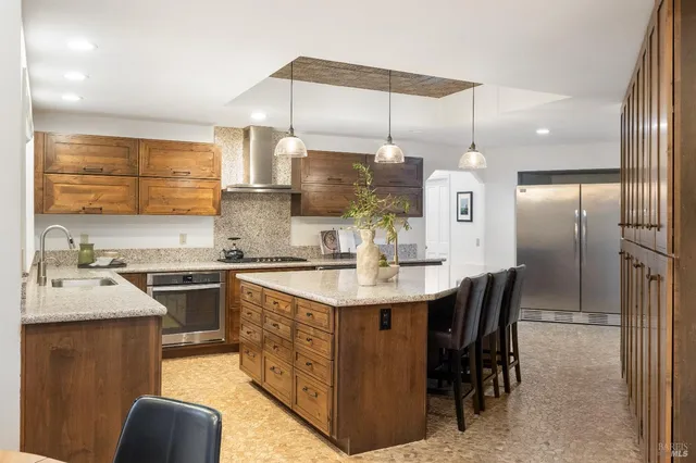 a kitchen with kitchen island granite countertop a sink a counter top space appliances and cabinets