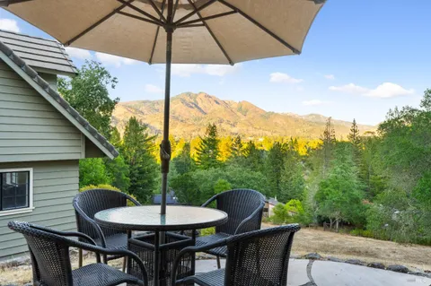 a backyard of a house with table and chairs under an umbrella