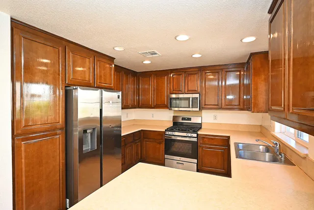 a kitchen with granite countertop stainless steel appliances a refrigerator a stove top oven and a sink