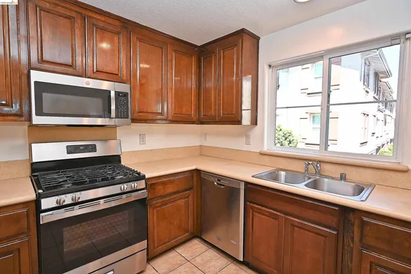 a kitchen with granite countertop cabinets stainless steel appliances a sink and window