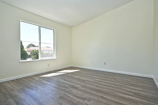 an empty room with wooden floor and windows