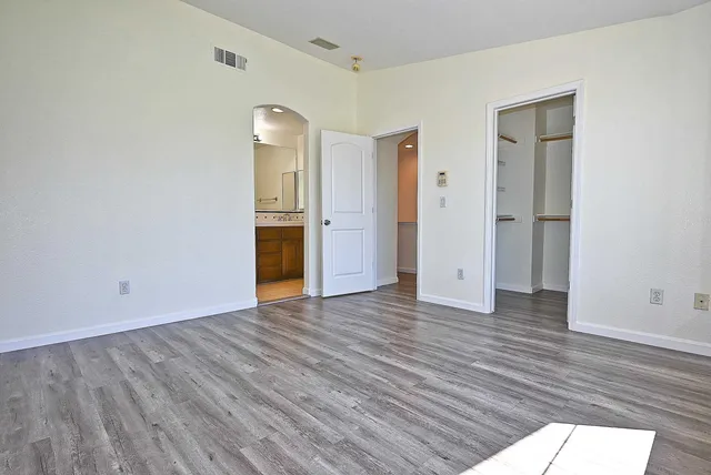 a view of an empty room with wooden floor and closet