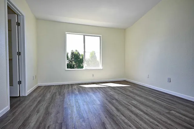 an empty room with wooden floor and windows