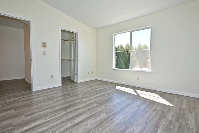 an empty room with wooden floor and windows