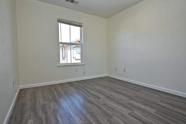 an empty room with wooden floor and a window