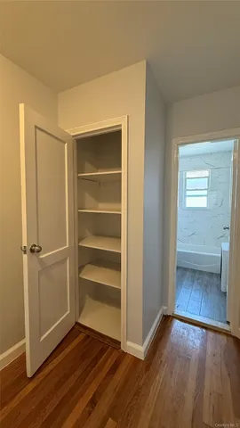 a view of an empty room with closet empty shelves and wooden floor