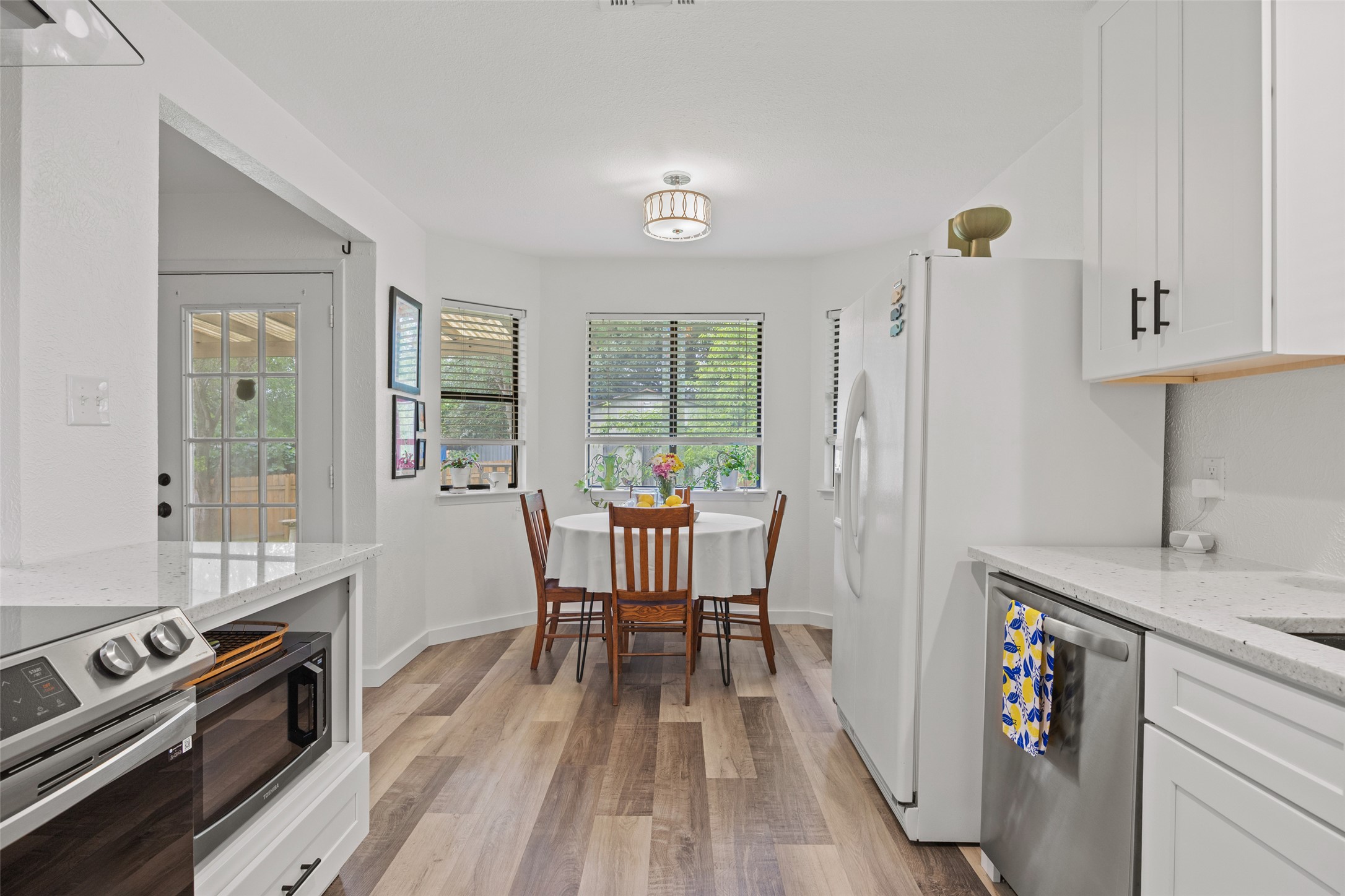 5506 South Pleasant Valley Road Austin, TX 78744 - Photo 7 of 25 A cheerful eat-in kitchen with wood-look flooring and sun-filled windows.