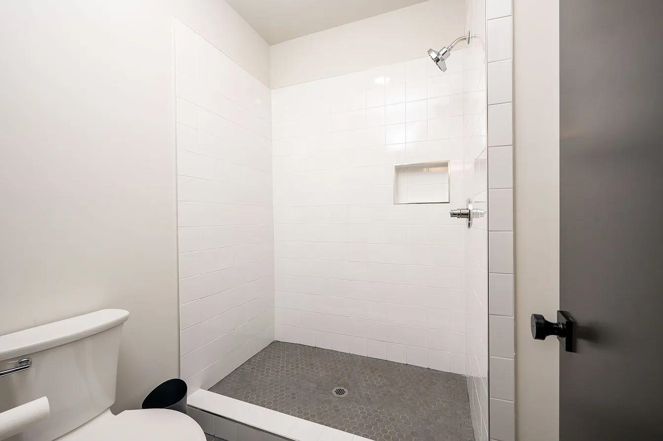 752 Meda Street Memphis, TN 38104 - Photo 13 of 18 Walk-in shower featuring white subway tile surround, integrated shower niche, and a grey hexagon tile floor