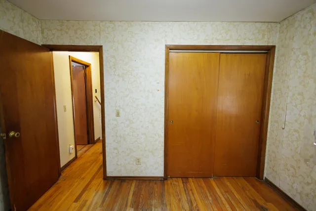 an empty room with wooden floor and entrance