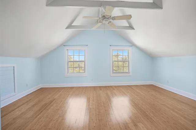 an empty room with wooden floor chandelier fan and windows