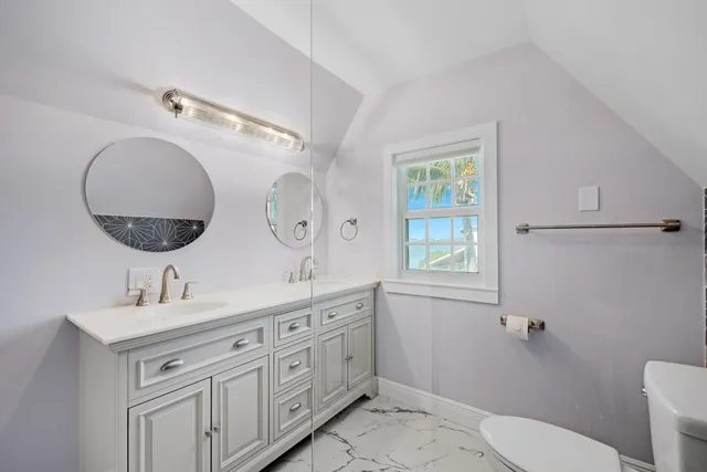 a bathroom with a double vanity sink toilet mirror and window