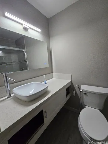 a bathroom with a granite countertop toilet sink and mirror