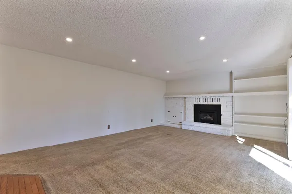 a view of an empty room with a window and a kitchen