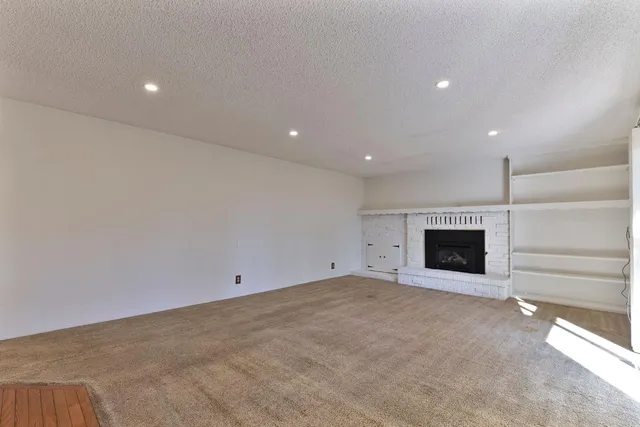 a view of an empty room with a window and a kitchen