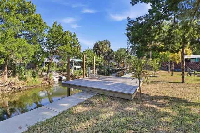 a backyard of a house with table and chairs potted plants and large trees