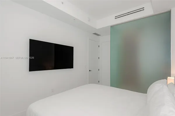 a bedroom with a bed and a flat tv screen on dresser
