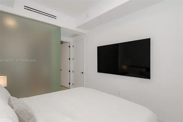 a bedroom with a bed and a flat tv screen on dresser