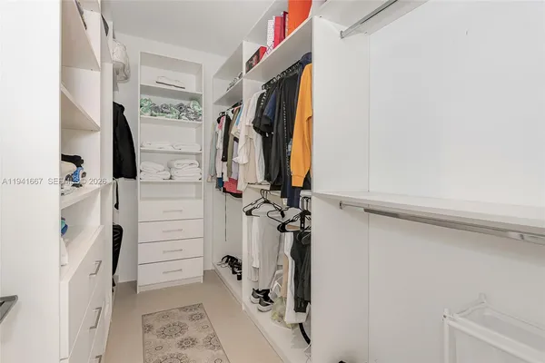 a view of walk in closet with clothes and shoes