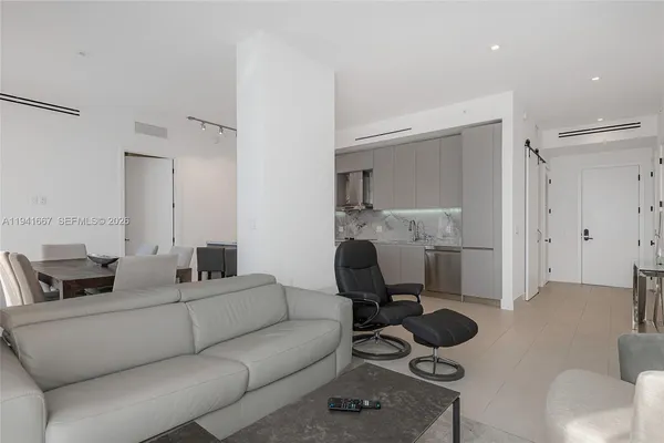 a living room with furniture and a view of kitchen