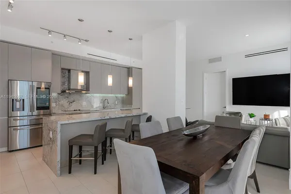 a kitchen with a dining table chairs and refrigerator