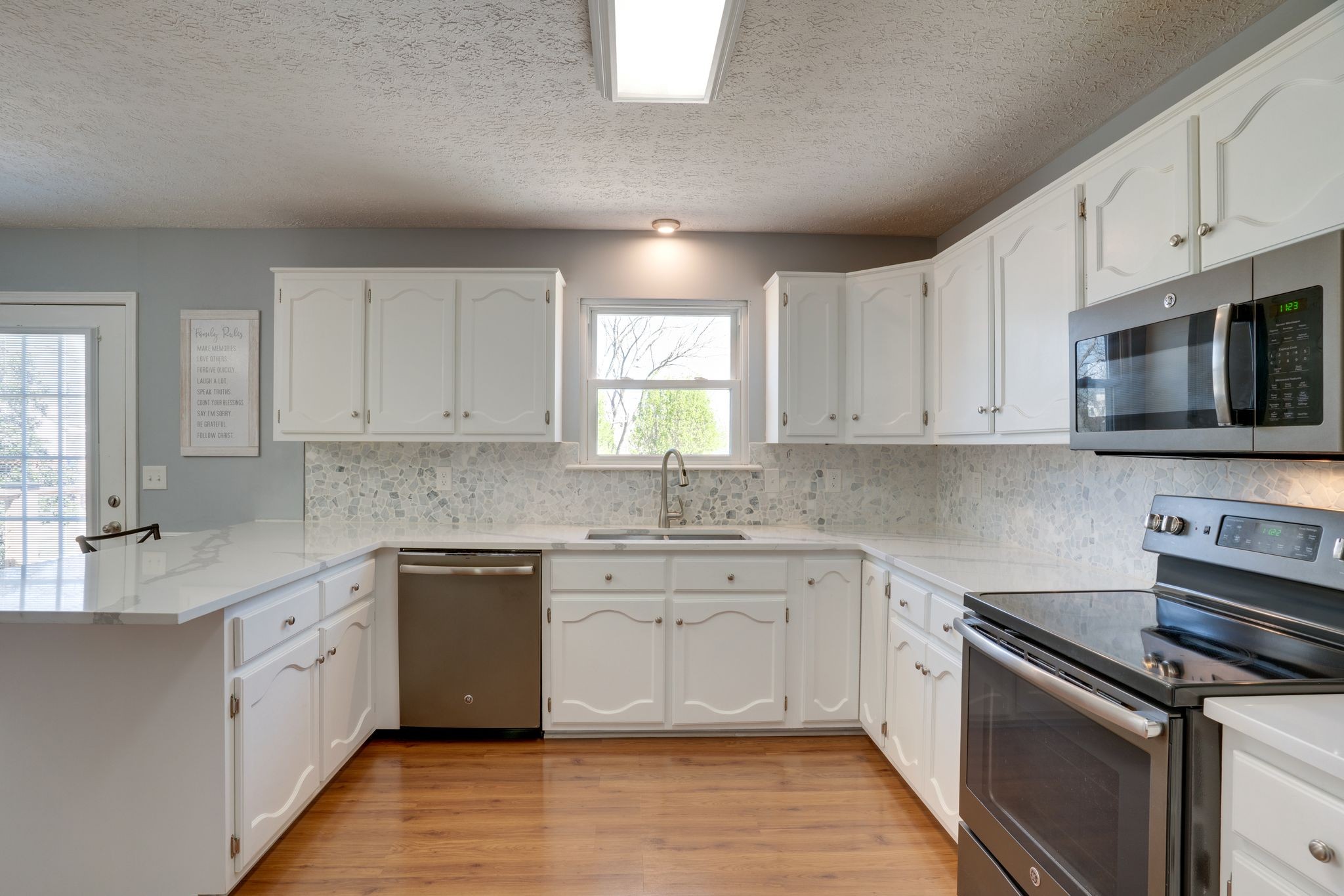 145 South Palmers Chapel Road White House, TN 37188 - Photo 7 of 30 a kitchen with stainless steel appliances granite countertop a stove top oven a sink dishwasher and white cabinets with wooden floor