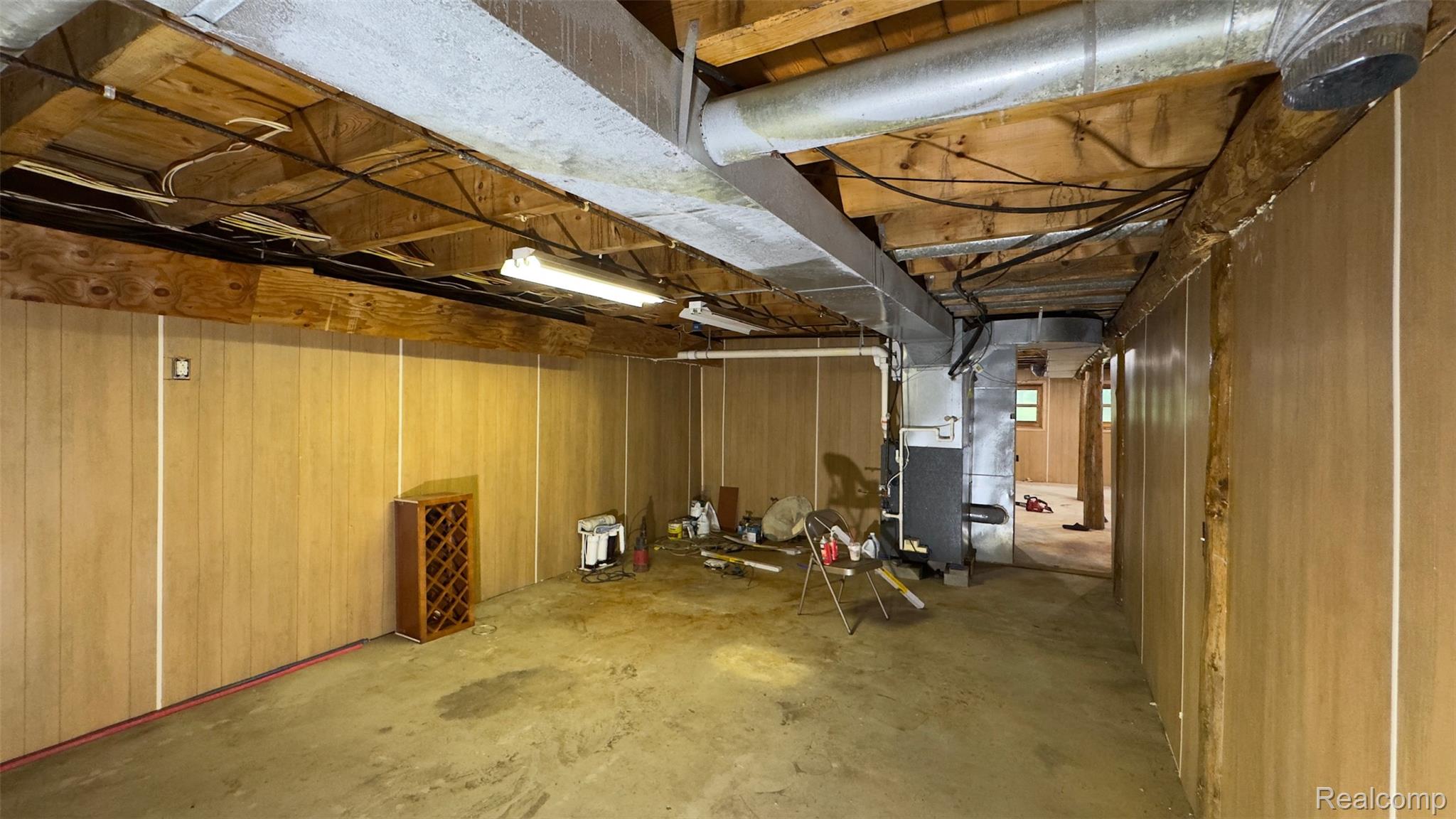 2608 East Sutton Road Metamora, MI 48455 - Photo 40 of 64 Spacious unfinished basement featuring paneled walls, concrete flooring, exposed ceiling joists, and visible ductwork