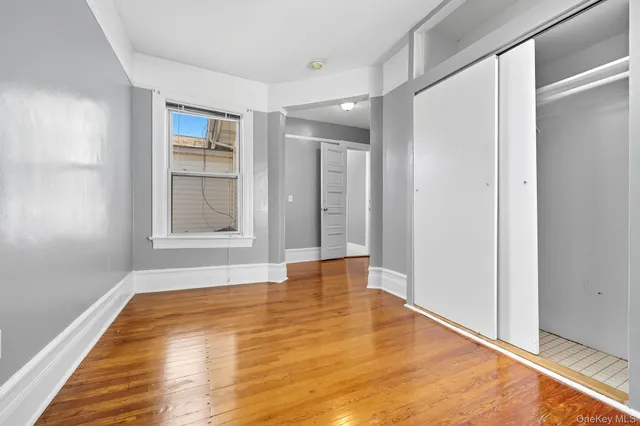 a view of an empty room with window and wooden floor