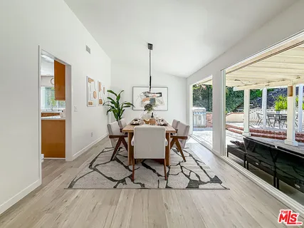 a dining room with furniture wooden floor a rug a potted plant and a chandelier