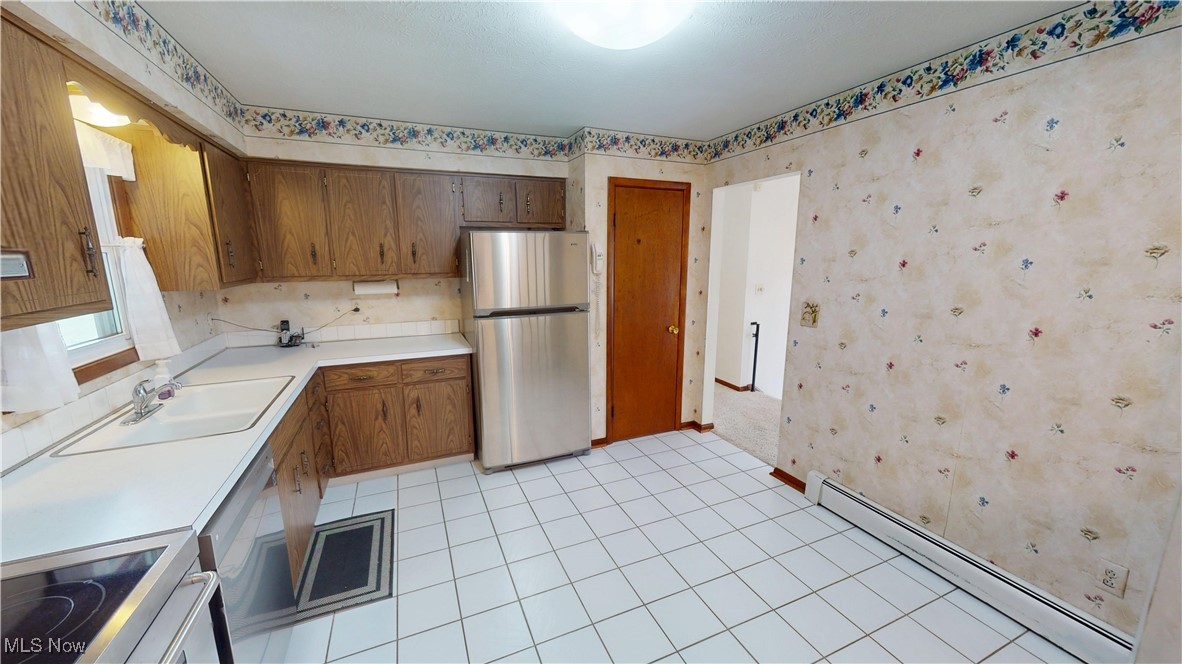 4444 Center Road Brunswick, OH 44212 - Photo 3 of 9 Kitchen with wallpapered walls, baseboard heating, appliances with stainless steel finishes, light countertops, and light tile patterned floors