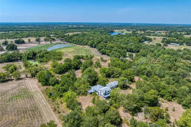 an aerial view of residential houses with outdoor space and trees